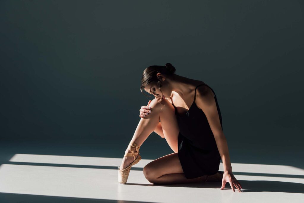 beautiful-ballerina-in-black-dress-sitting-in-sunl-ATBAEKJ.jpg